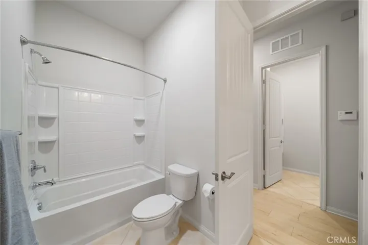 Guest Bathroom Features a Classic Tub/Shower Combo with Built-In Shelving and Neutral Tile Flooring