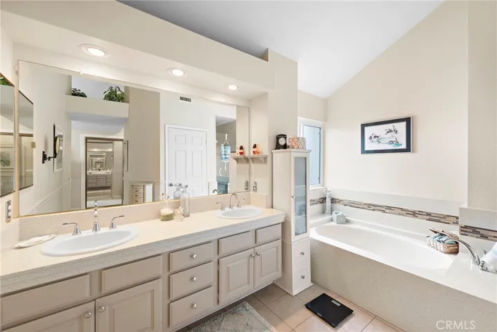 Light and bright primary bathroom with high ceilings, double sinks, spacious soaking tub, separate shower and commode.