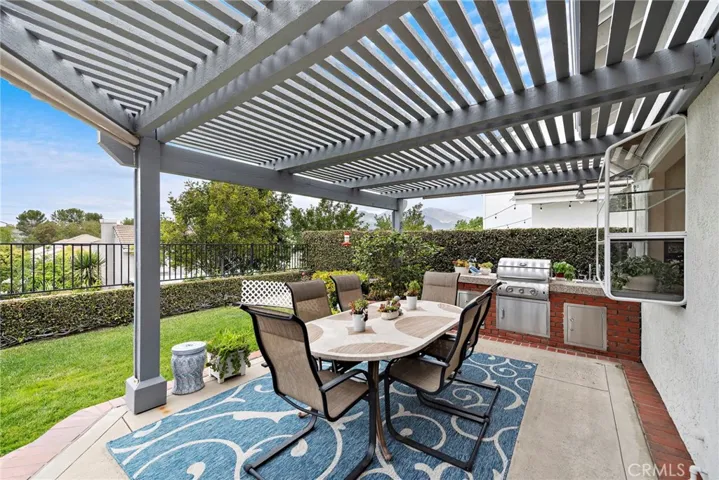 The outdoor dining adjacent to the outdoor kitchen with the upgraded BBQ, storage, sink and stone countertop.