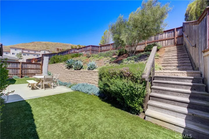 Stairs along the side of the yard lead to the upper seating area out back.