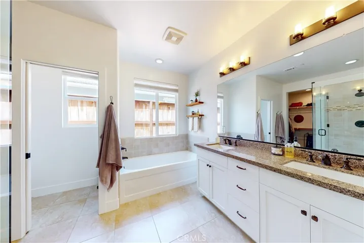 Primary bathroom with dual vanity and tiled flooring.