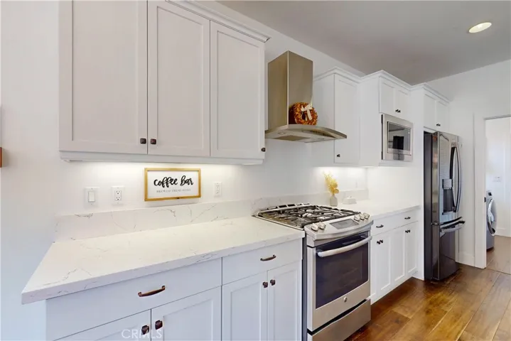 Gas stove with industrial style overhead vent.