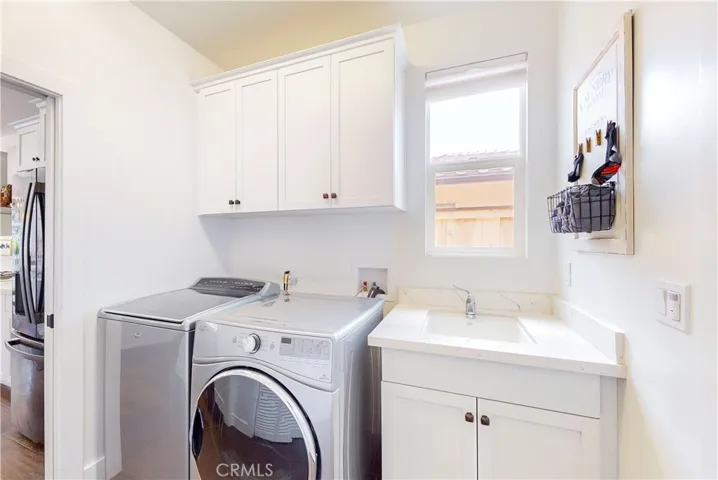 Located between the kitchen and garage, the laundry room includes a sink and built-in storage