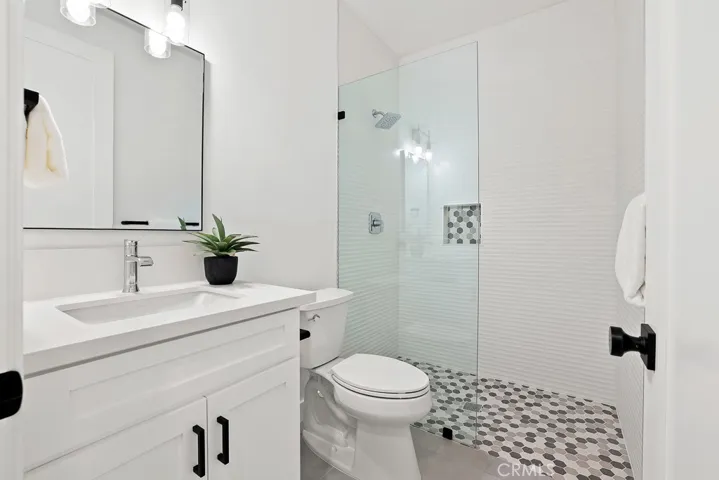 Chic and modern guest bathroom featuring sleek matte black hardware, stylish lighting, and a crisp white vanity—designed for both comfort and aesthetics.
