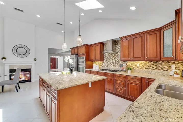 The chef's dream kitchen is open to the breakfast area and enormous family room w/custom built-in entertainment center, and is appointed w/a grand center island, custom cabinetry, mosaic tile backsplash, and top-of-the-line stainless appliances (5-burner gas cooktop, dishwasher, Jenn-Air oven & combo microwave/oven).