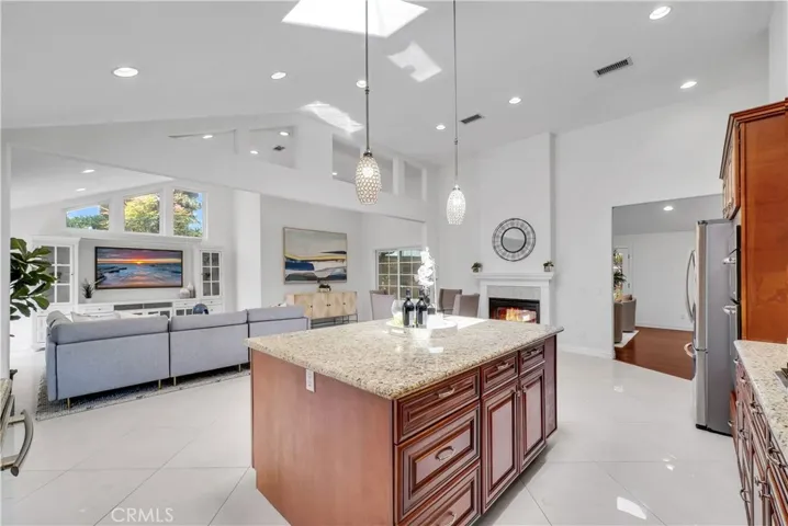 gourmet kitchen with granite countertops, a grand center island, custom cabinetry, mosaic tile backsplash, and top-of-the-line stainless appliances (5-burner gas cooktop, dishwasher, Jenn-Air oven & combo microwave/oven), plus Double Stainless Sinks