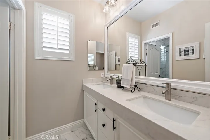 Remodeled upstairs secondary bathroom with double sinks and separate shower/tub with glass door enclosure