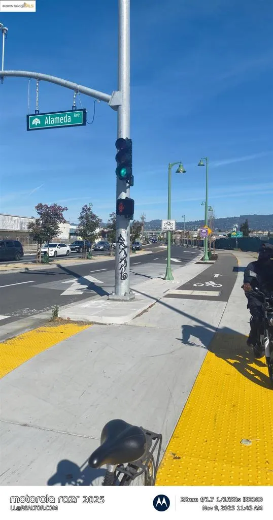 View of asphalt street with sidewalks, traffic lights, street lights, curbs, and traffic signs
