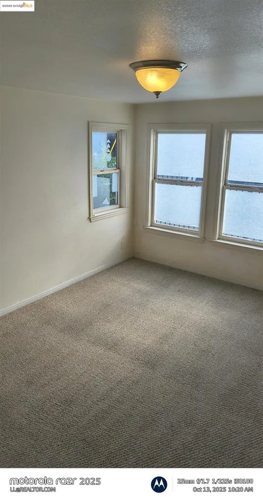 Carpeted spare room with a textured ceiling and baseboards