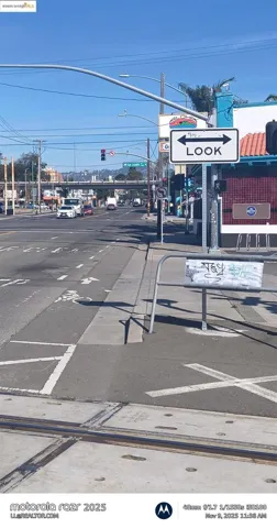View of asphalt street featuring traffic lights, sidewalks, street lights, and curbs