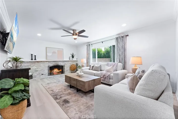 Formal living room with fireplace with large mantle, ceiling fan, recessed lighting, a large window looking out to the backyard!