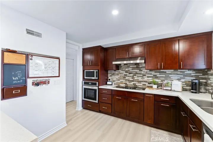 Dark wood cabinetry, quartz counter tops, tile backsplash, stainless steel, appliances, and new LVP flooring round out this amazing ktichen!