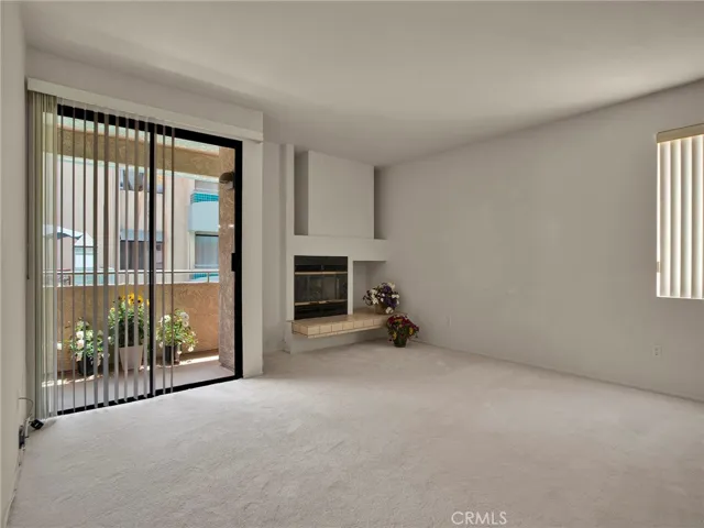 Living room with fireplace, sliding door to patio with views of the courtyard, pool & spa and an additional window for great natural light.