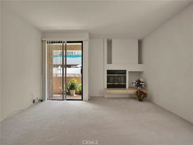 Living room with fireplace, sliding door to patio with views of the courtyard, pool & spa and an additional window for great natural light.