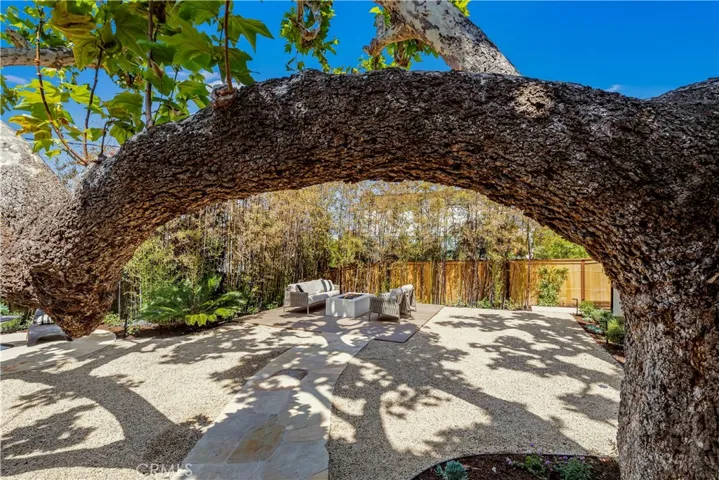 THE STONE PATH LEADS UNDER A NATURAL ARCH OF THE DECADES-OLS SYCAMORE INVITES YOU TO EXPLORE THIS OUTDOOR OASIS.