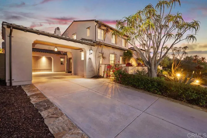 Long driveway with porte-cocher leads to multiple garages and parking for multiple cars.