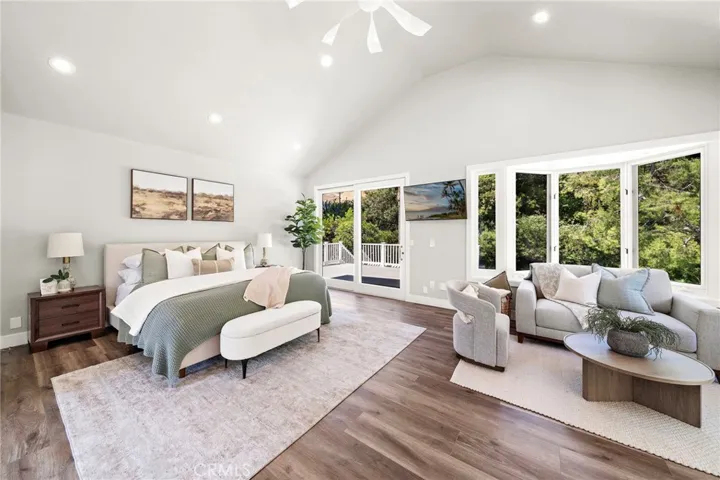 Upstairs primary retreat with soaring ceilings and windows framing tree top views