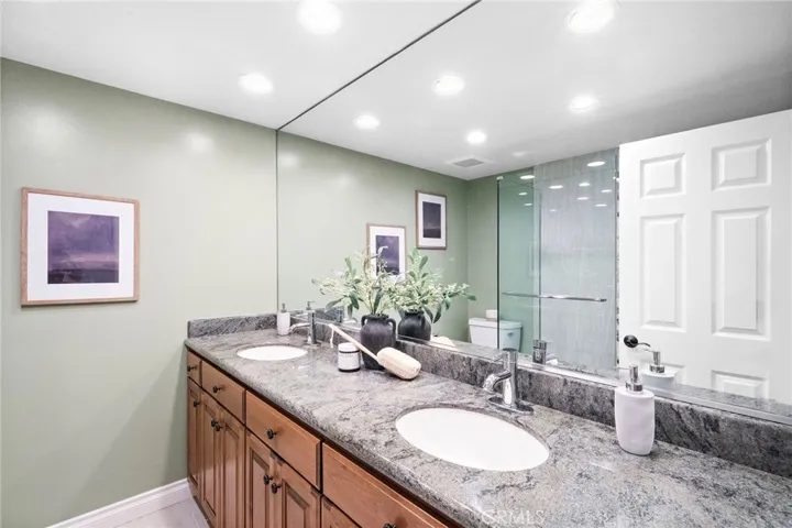 Hall bathroom near downstairs bedrooms with dual sinks and shower