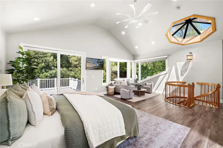 Primary suite with skylight and slider door leading to deck with tree top views