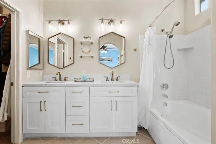 Remodeled Primary Bathroom with white shaker cabinets, quartz countertops, matte gold finishes.