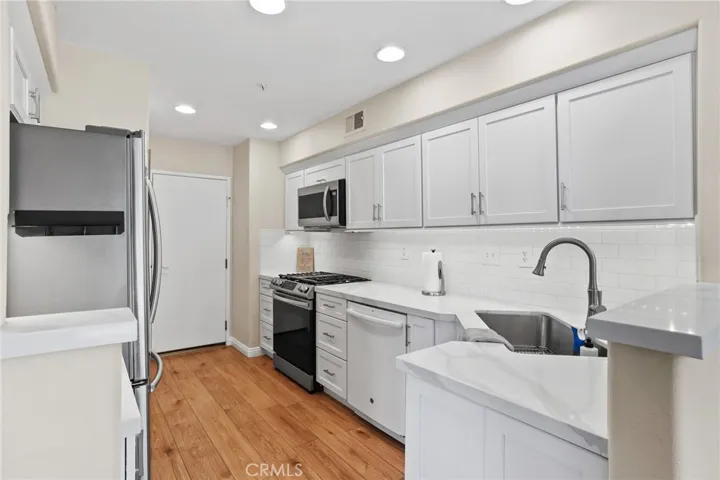 Remodeled white shaker cabinets, quartz countertops, single basin sink.