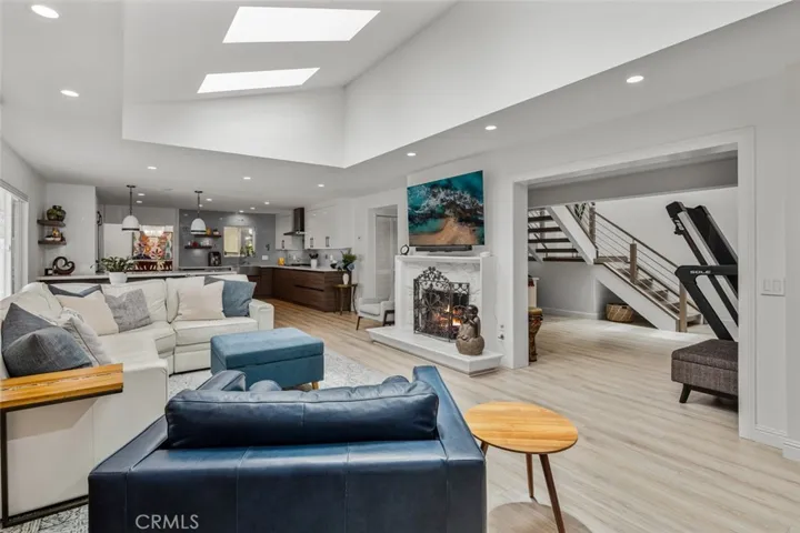 Looking the length and the width. To right is a very usable space that in original model was an exterior patio. The stairs are to the loft area. At end of fireplace is hallway to secondary bedrooms.