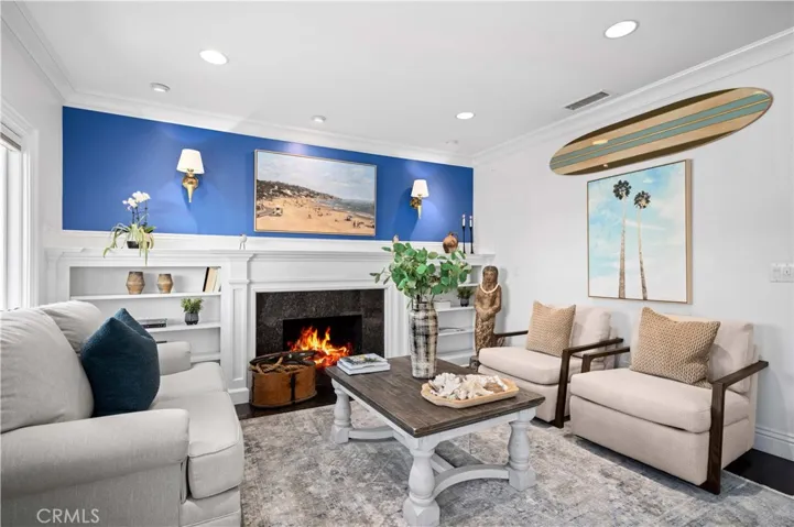 The inviting living room is anchored by a cozy fireplace and custom built-ins, flowing effortlessly into the dining area and a fully equipped kitchen with stainless steel appliances and timeless cottage charm.