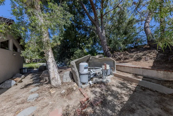 pool equipment on very east side of yard is hidden behind hollowed stone cave; 3 pumps, new heater; light; hidden from pool and house