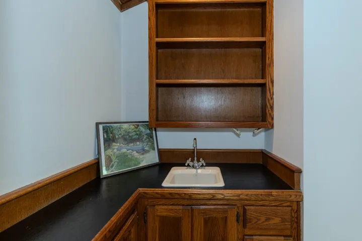Primary suite bar area features sink and leather countertop