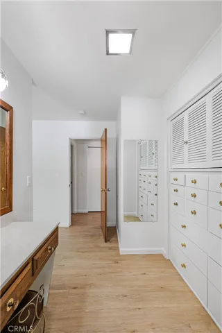 Dressing area with so many drawers and a mirror, along with a sit down vanity.