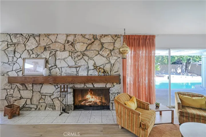 Fireplace in living room with custom mantle. Sliding glass door to pool and backyard