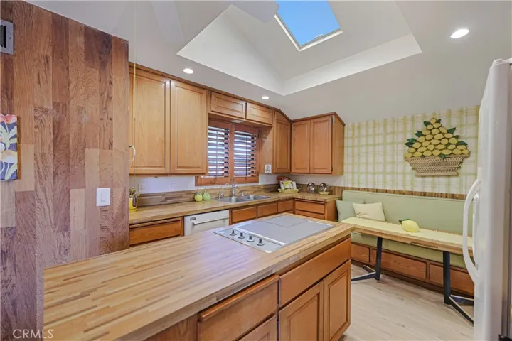 Kitchen with built-in breakfast seating, and island. Skylight lets in the sunshine - light and bright! Wood shutters on the window.