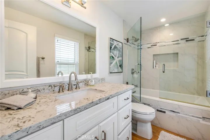 Upstairs hall full bathroom including quartz counters, shower in bathtub and glass shower doors.