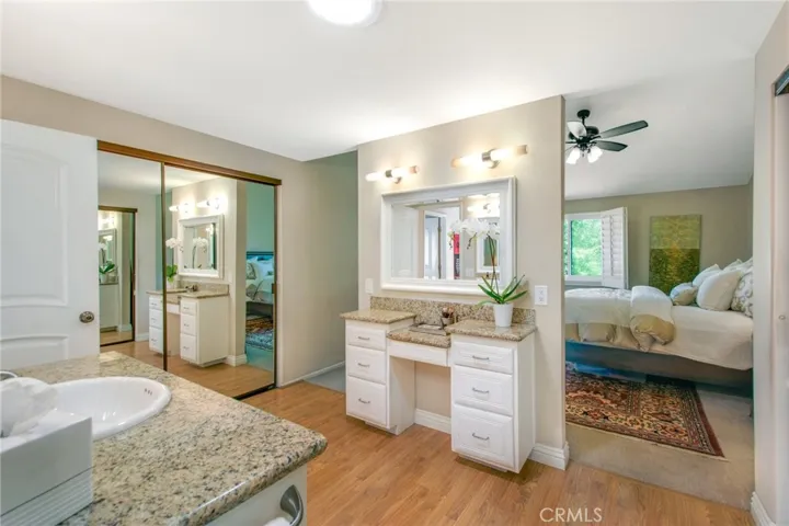 Primary bathroom including quartz counters, vanity mirror and makeup quartz counter and two of two mirrored closet sliders.