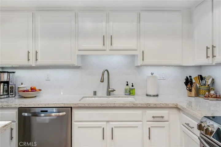 Kitchen space highlighting quartz countertop and herringbone back splash.