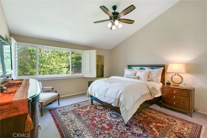 Upstairs Primary bedroom including vaulted ceiling, ceiling fan, large dual pane window to allow for plenty of natural light to flood in and plantation shutters for privacy and Berber carpet.