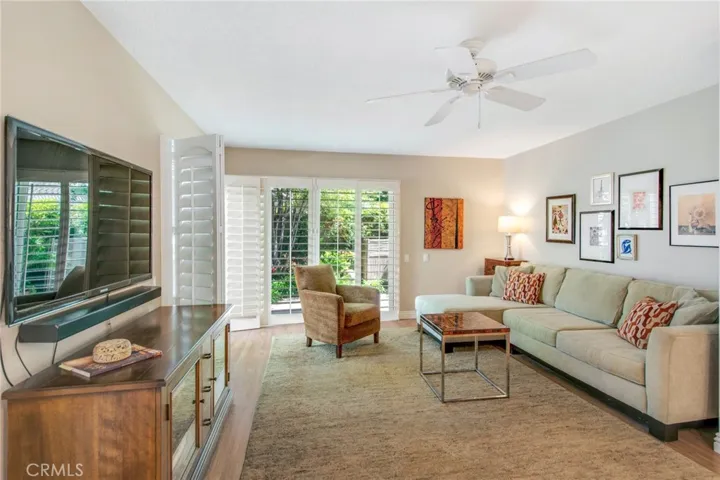 Family room including ceiling fan and dual pane sliders and plantation shutters to back patio.