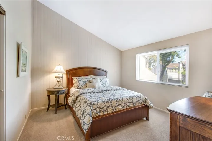 Upstairs Guest bedroom including vaulted ceiling, large dual pane window and horizontal blinds for privacy, Berber carpet and vertical shiplap accent wall.