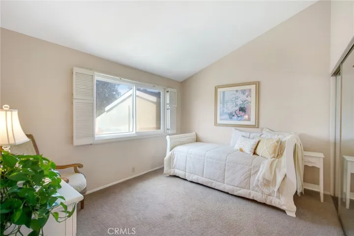 Upstairs bedroom including vaulted ceiling, large dual pane window to allow for natural light to flood in and plantation shutters for privacy, Berber carpet and glass sliding closet doors.