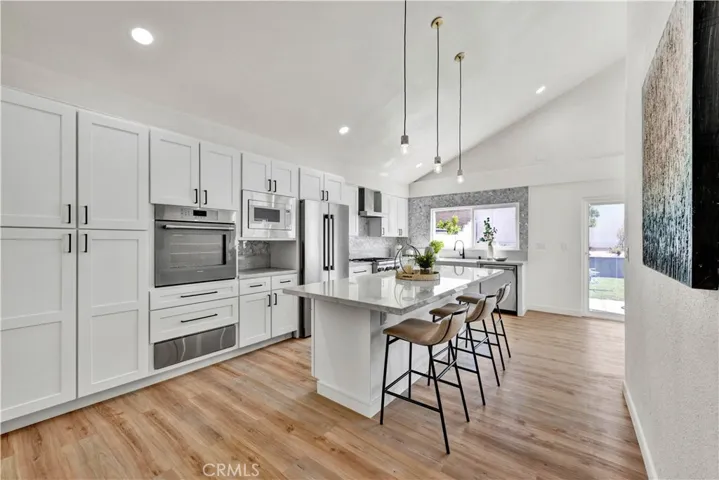 wrap-around seating, chic pendant lighting, custom white shaker self-closing cabinetry