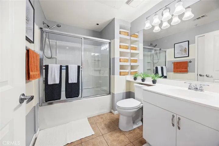 En suite primary bathroom conveniently opens to the living room. Spacious shower over tub combination has glass enclosure
