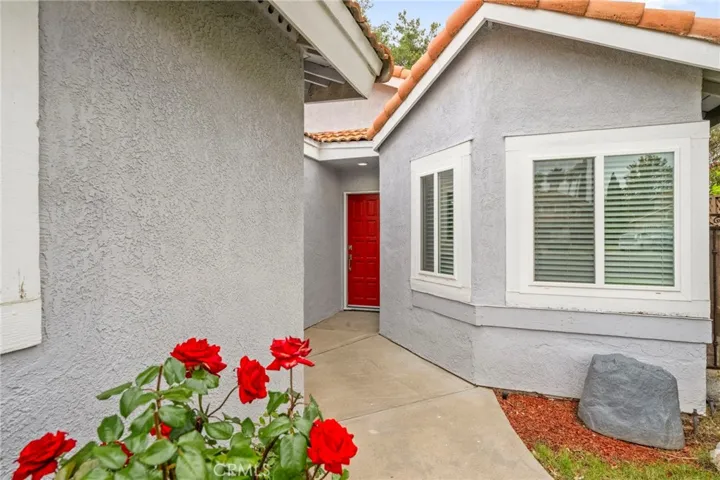 Red and white roses line the walkway to the front door.