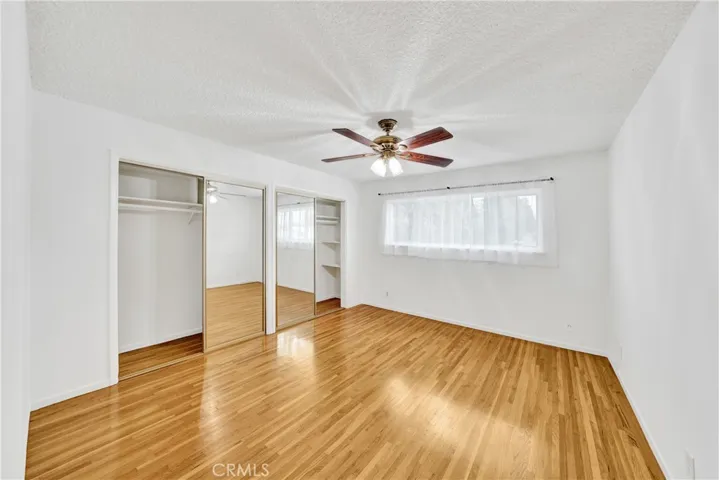 Ceiling fan, shelving in bedroom closet, mirrored doors and a newer vinyl window.