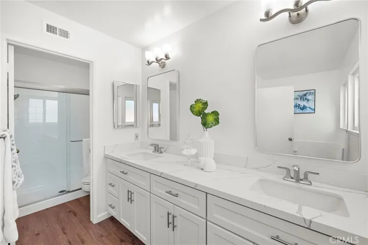 a fully renovated bath with custom vanity, quartz counters, and a separate newly glazed  walk-in shower with new glass doors and separate soaking tub.