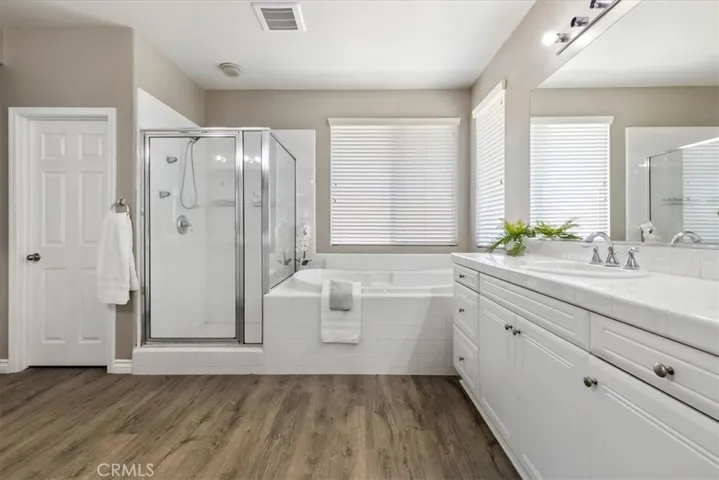Luxurious primary bathroom featuring a spacious separate shower, a large soaking tub, and dual sinks for ultimate comfort and convenience