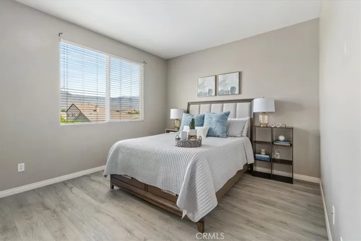 This cozy upstairs bedroom offers a peaceful retreat with picturesque views of the nearby hills and rooftops. Natural light pours in through the large window, creating a warm and inviting atmosphere.