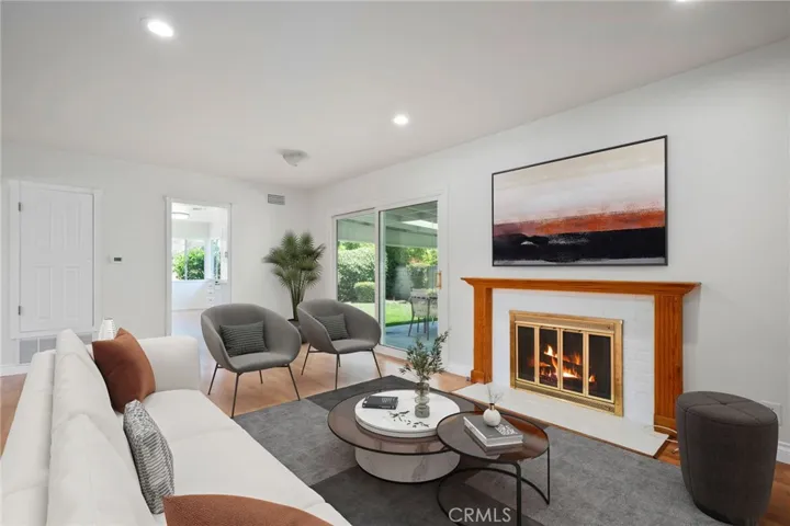 A separate family room offers an ideal setting for gatherings, complete with a cozy fireplace and a newer sliding glass door that frames peaceful views of the beautifully landscaped backyard.