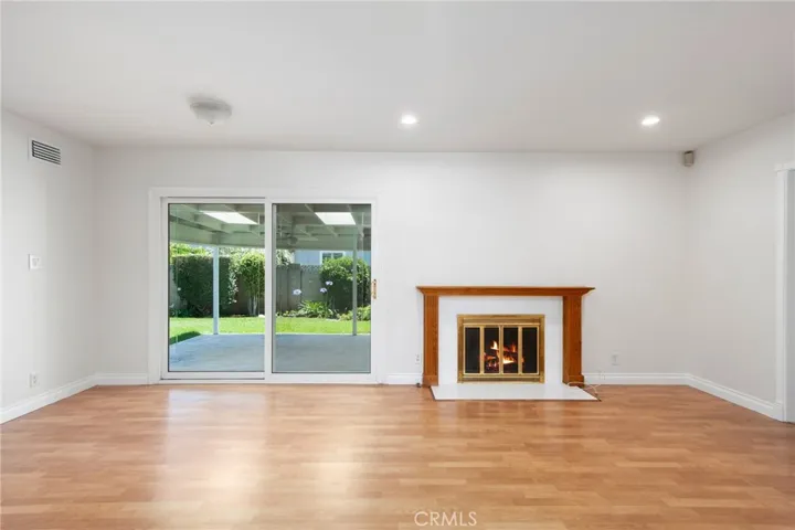  A separate family room offers an ideal setting for gatherings, complete with a cozy fireplace and a newer sliding glass door that frames peaceful views of the beautifully landscaped backyard.