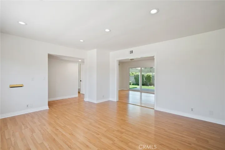 ** without staging**  Large, light-filled living room adorned with rich hardwood flooring and freshly painted interiors that create a warm, move-in ready atmosphere.