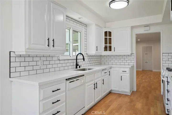 The kitchen has been tastefully upgraded with freshly painted cabinets, sleek quartz countertops, and a custom tile backsplash, giving it a clean, contemporary look.
